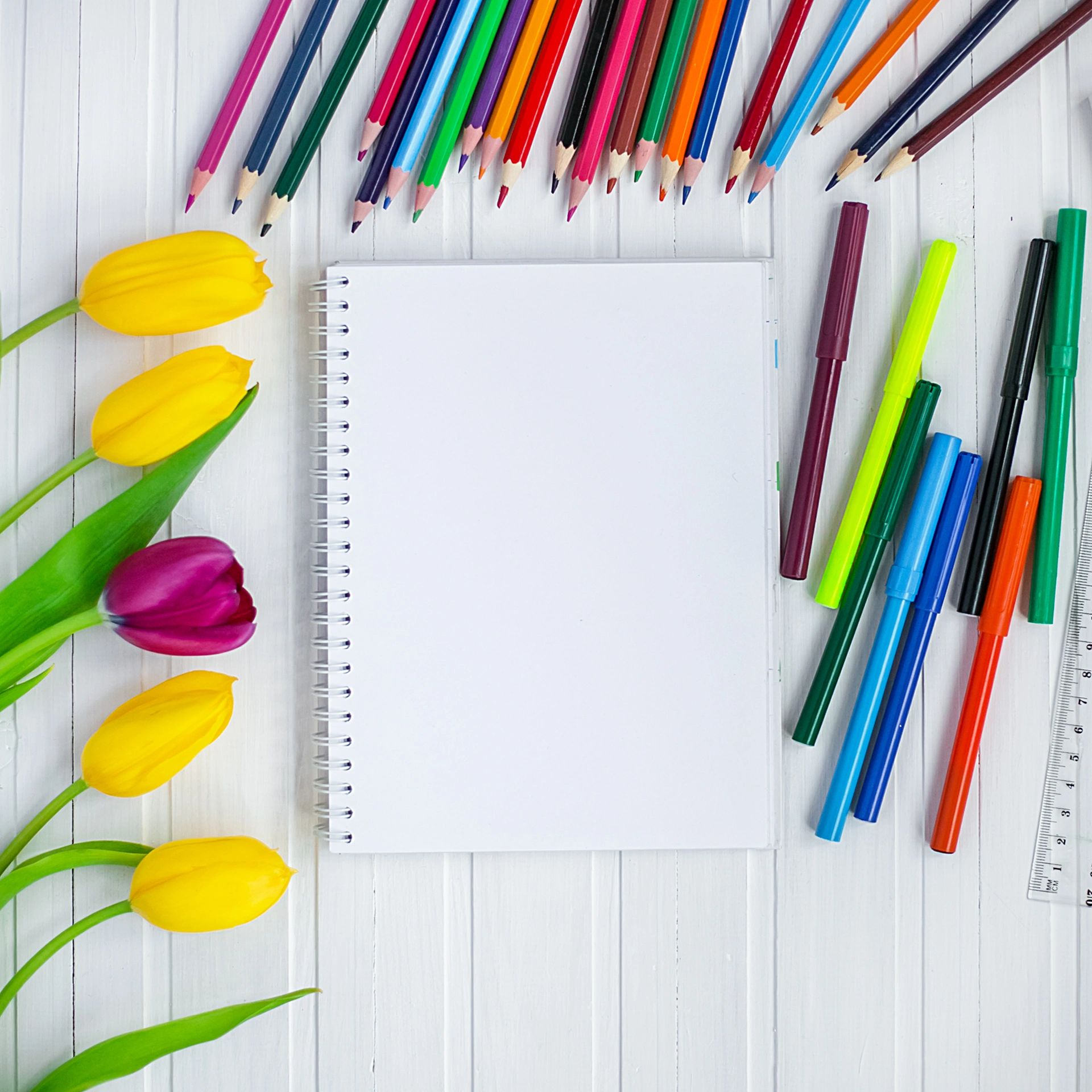 Colouring pencils on a table beside blank paper